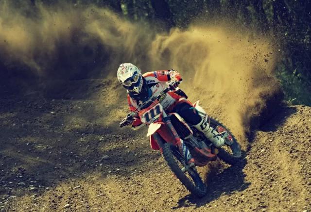 Gambar motor trail bewarna merah sedang melaju di sebuah gurun.